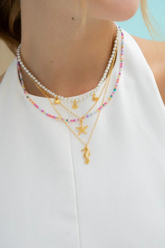 Layered handmade necklaces with gold charms, pearls, and colorful beads by Jabatzelet