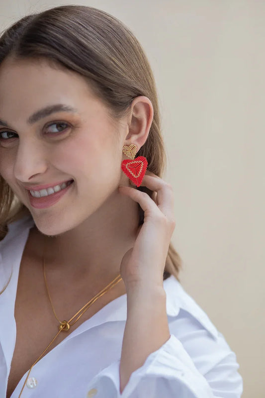 Woman wearing handmade red beaded heart earrings and gold necklace by Jabatzelet jewelry