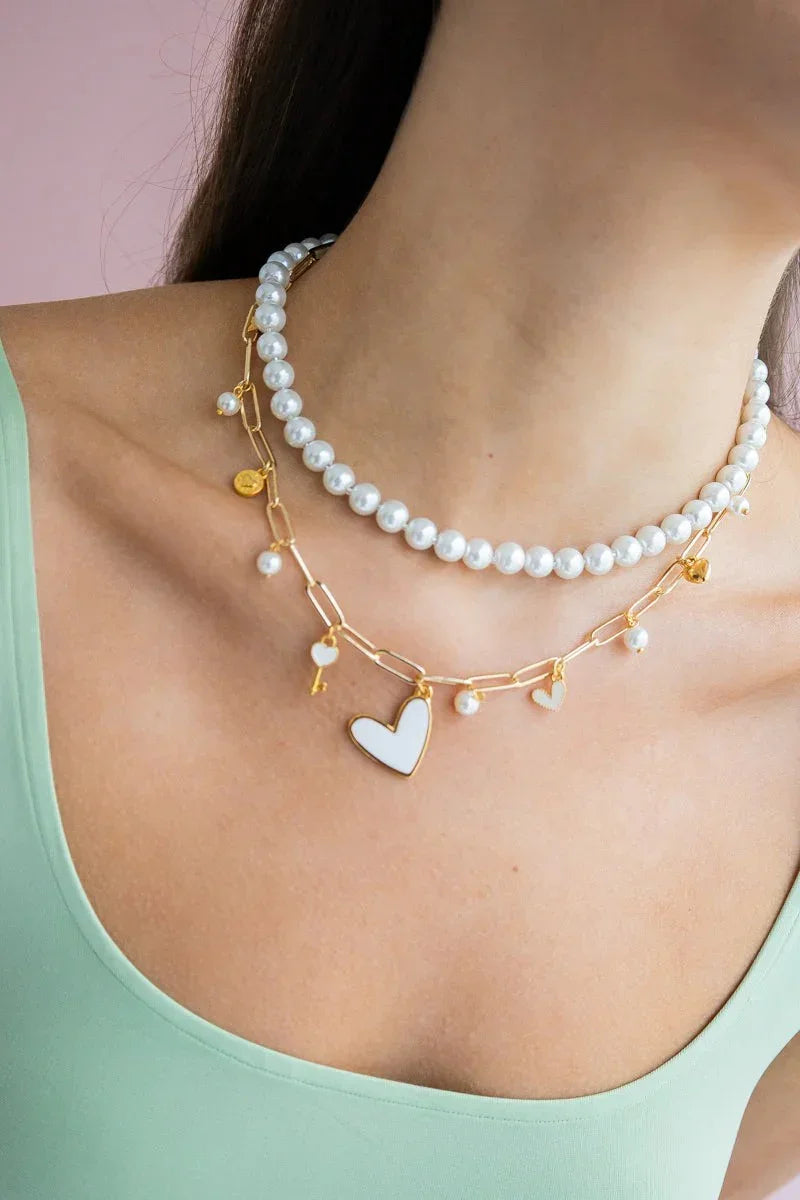 Woman wearing layered handmade pearl necklace and gold heart charm chain, Jabatzelet jewelry