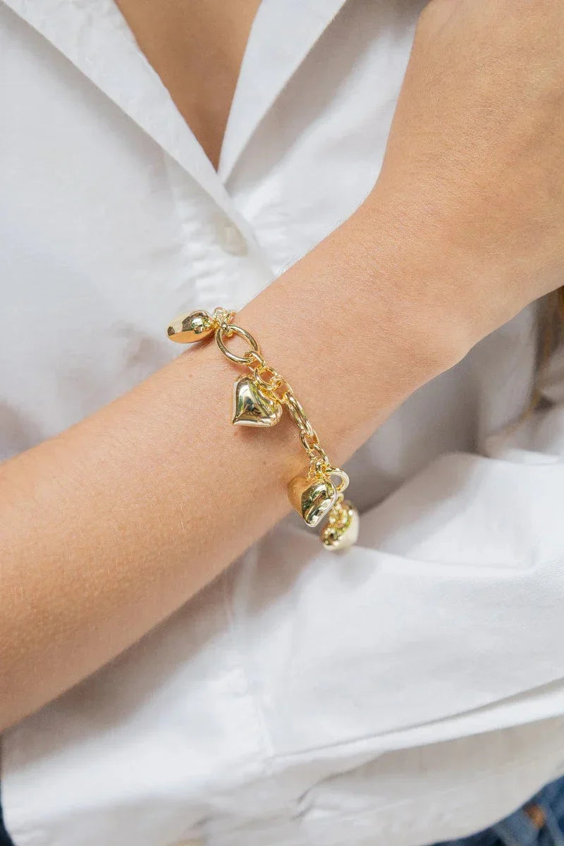 Hand wearing handmade gold heart charm bracelet from Jabatzelet jewelry collection