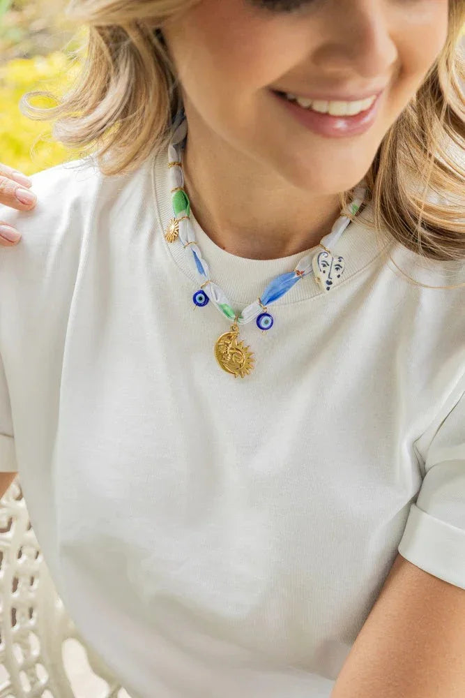Woman wearing handmade Jabatzelet necklace with gold sun charm and blue accents