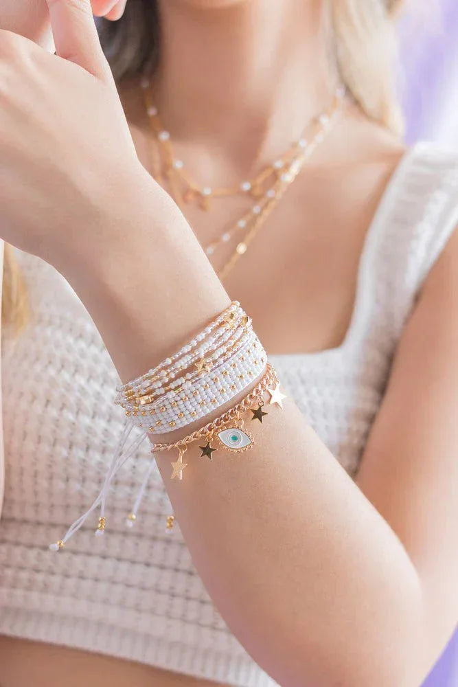 Handmade beaded bracelets with gold charms and evil eye detail on woman's wrist, Jabatzelet jewelry
