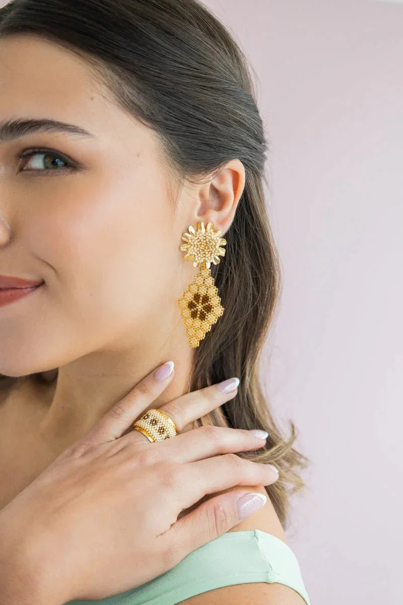 Woman wearing handmade gold beaded earrings and matching ring from Jabatzelet jewelry