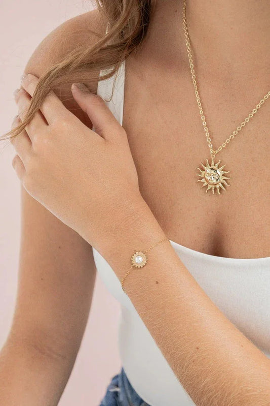 Woman wearing handmade gold sun pendant necklace and matching sun bracelet by Jabatzelet jewelry