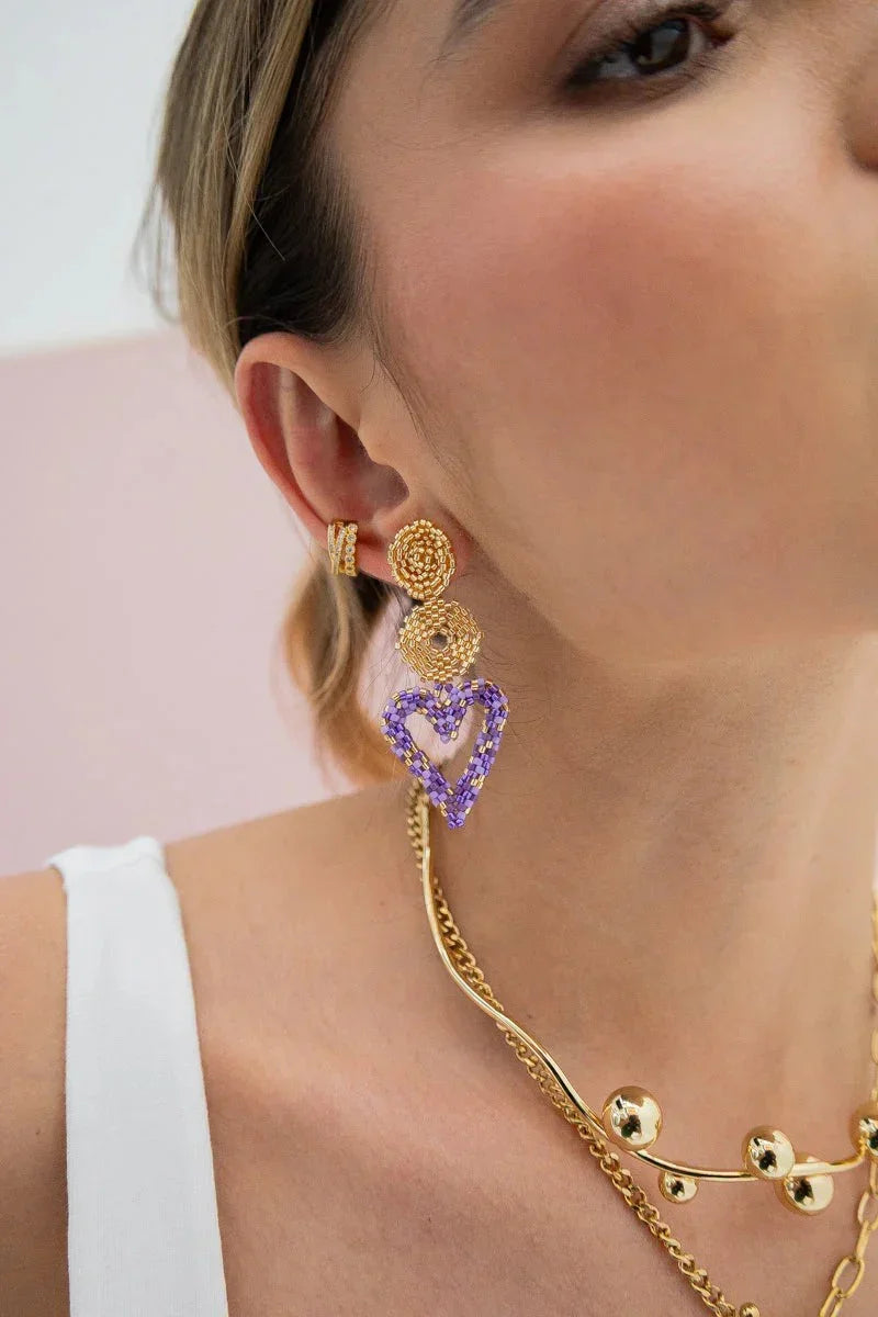 Close-up of woman wearing handmade gold and purple beaded earrings and gold necklace from Jabatzelet jewelry.