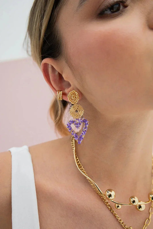 Close-up of woman wearing handmade gold and purple beaded earrings and gold necklace from Jabatzelet jewelry.