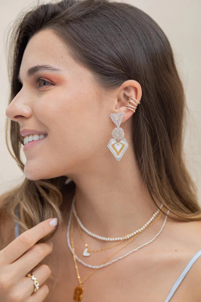 Woman wearing Jabatzelet handmade jewelry, including beaded earrings, layered necklaces, and gold ring