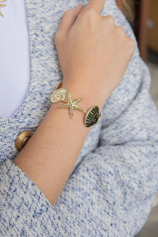 Handmade gold bracelet with starfish and shell charms on wrist, Jabatzelet jewelry